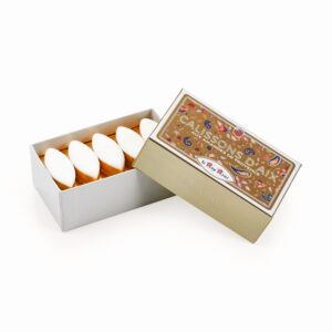 Open decorative box of Calissons d'Aix with white almond-shaped candies arranged in a row.