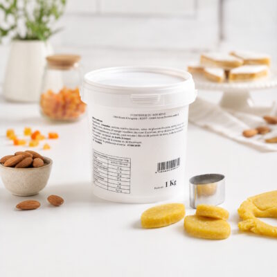 White 1 kg container with a printed label on a white surface, surrounded by an almond bowl, yellow cookies, and a metal cookie cutter nearby.