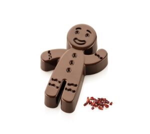 Milk chocolate gingerbread man on a white background with a small pile of red chili flakes beside him.