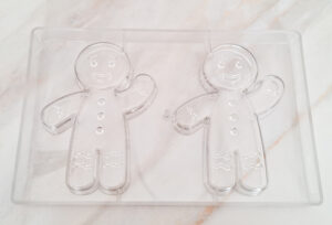 Clear plastic packaging tray with two large smiley-face shapes and attached arms on a pale surface.