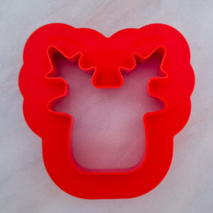Red silicone cookie cutter with a donut-shaped outer edge and scalloped inner cutouts on a gray background.