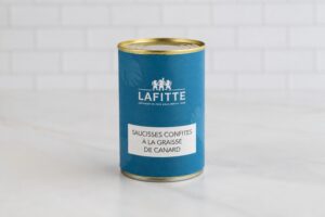 Blue Lafitte can of confit sausages in duck fat with a white label showing the French name Saucisses confites à la graisse de canard on a light surface.