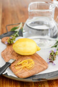 Wasser mit Gartenkräutern und Blüten aromatisieren Kräuterwasser Rezept Schritt 5 Zitrone Schälen Zitronenzeste 200x300